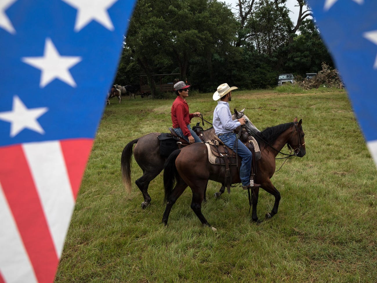 Men on horseback ride through a field after participating in the 168th annual Round Top Fourth of July Parade on July 4, 2018 in Round Top, Texas.