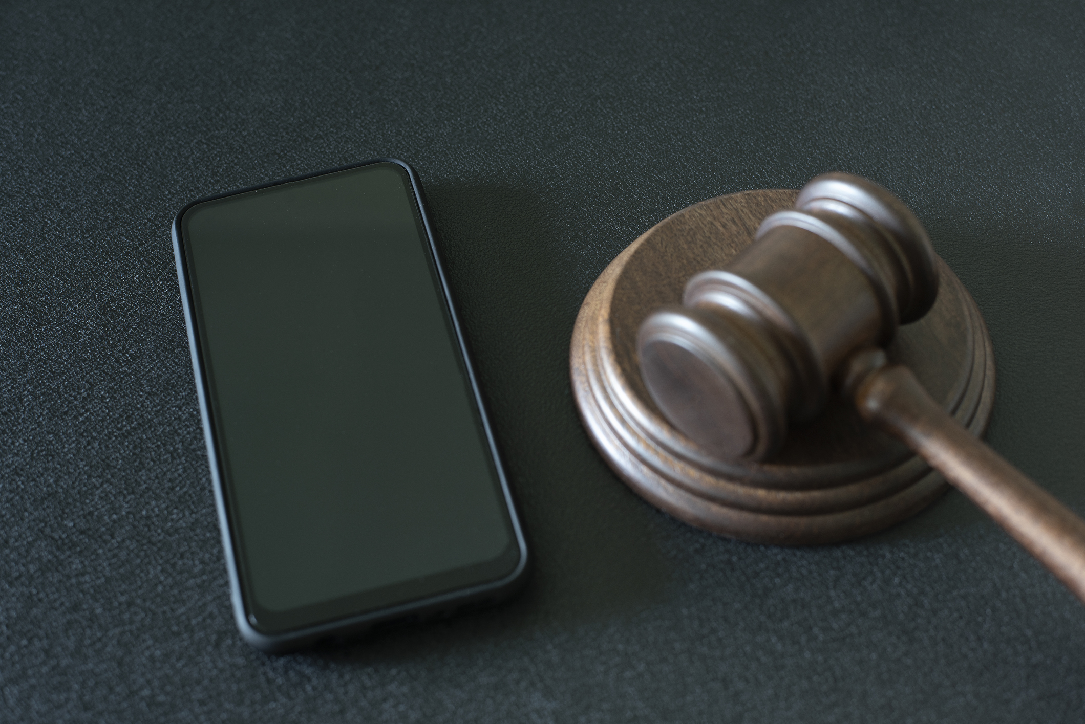Smartphone and judge gavel on black background
